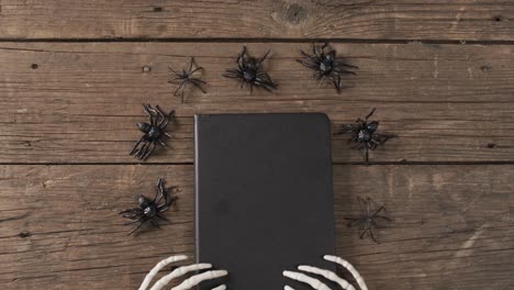 Vídeo-De-Manos-De-Esqueleto-De-Halloween,-Cuaderno-Y-Arañas-Con-Espacio-Para-Copiar-Sobre-Fondo-De-Madera