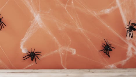 Video-of-halloween-spiders-and-spider's-web-and-copy-space-on-orange-background