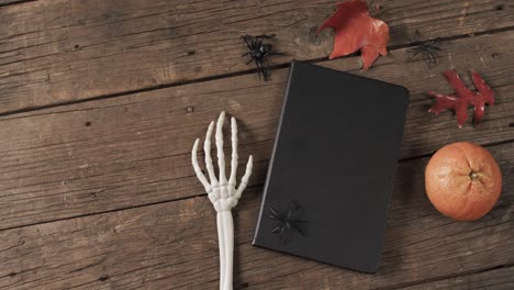 Vídeo-De-Manos-De-Esqueleto-De-Halloween,-Cuaderno-Y-Decoraciones-Con-Espacio-Para-Copiar-Sobre-Fondo-De-Madera