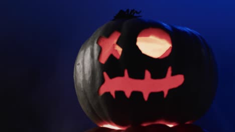 Video-of-halloween-carved-pumpkin-and-smoke-with-copy-space-on-blue-background