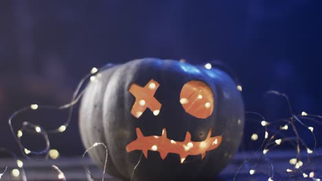 Video-of-halloween-carved-pumpkin-and-fairy-lights-with-copy-space-on-blue-background