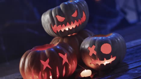 Video-of-halloween-carved-pumpkins-and-smoke-with-copy-space-on-blue-background