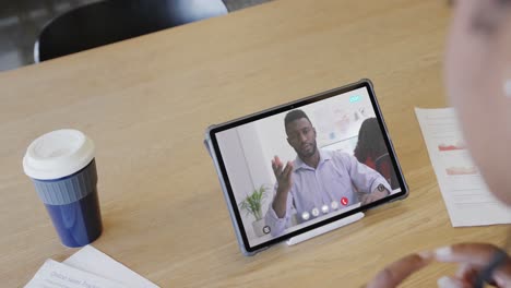Caucasian-businesswoman-on-tablet-video-call-with-african-american-male-colleague-on-screen