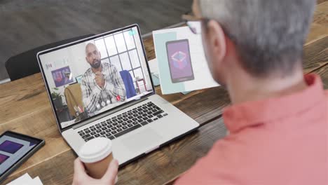 Caucasian-businessman-on-laptop-video-call-with-african-american-male-colleague-on-screen