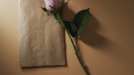 Video-Einer-Rosa-Rose-Mit-Braunem-Umschlag-Und-Kopierraum-Auf-Gelbem-Hintergrund
