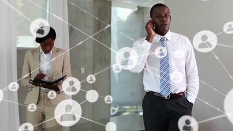 Animation-of-network-of-profiles-over-african-american-businessman-talking-on-smartphone-at-office