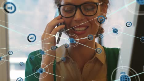 Animation-of-network-of-digital-icons-over-happy-caucasian-woman-talking-on-smartphone-at-office