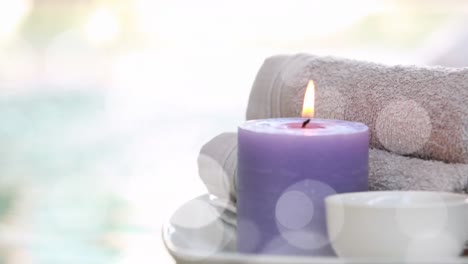 Animation-of-white-light-spots-over-lit-candle-and-towels