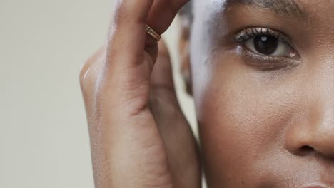 Nahaufnahme-Des-Auges-Einer-Afroamerikanischen-Frau-Mit-Kurzen-Dunklen-Haaren-Auf-Grauem-Hintergrund,-Zeitlupe