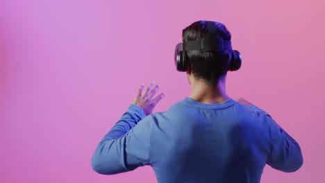 Video-of-biracial-man-using-vr-headset-on-pink-and-purple-background