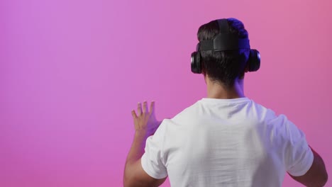 Video-of-biracial-man-using-vr-headset-on-pink-and-purple-background