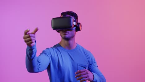 Video-of-african-american-man-using-vr-headset-on-pink-and-purple-background