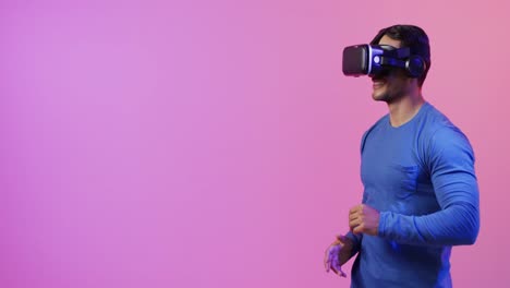 Video-Eines-Kaukasischen-Mannes,-Der-Ein-VR-Headset-Auf-Rosa-Und-Violettem-Hintergrund-Verwendet