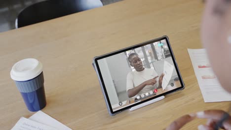 Caucasian-businesswoman-on-tablet-video-call-with-african-american-male-colleague-on-screen