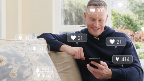Animation-of-social-media-icons-floating-over-happy-caucasian-man-using-smartphone-at-home
