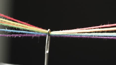 Video-Von-Mikro-Von-Regenbogenfarbenen-Fäden,-Die-Durch-Die-Nadel-Laufen,-Mit-Kopierraum-Auf-Schwarzem-Hintergrund