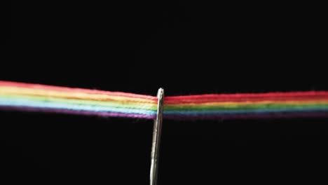Video-of-micro-of-rainbow-coloured-threads-going-through-needle-with-copy-space-on-black-background