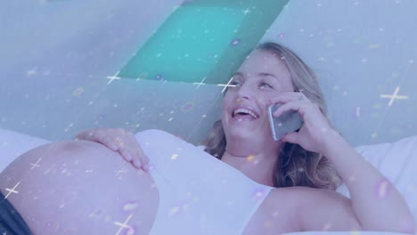 Interference-and-data-over-happy-pregnant-caucasian-woman-on-bed-talking-on-smartphone