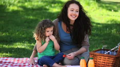 Mom-and-daughter-enjoying-strawberries-sitting-on-the-tablecloth