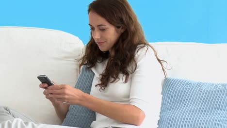 Portrait-of-a-hispanic-woman-writing-a-text-message-on-her-cellphone-on-the-sofa