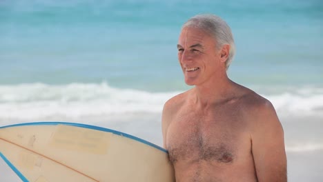 Elderly-man-looking-at-the-horizon-with-a-surfboard