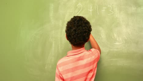 Cute-pupil-writing-maths-on-chalkboard