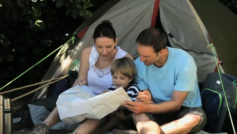 Family-looking-at-a-map-near-a-tent