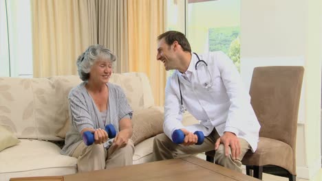 Young-doctor-showing-to-a-old-woman-the-use-of-dumbbells