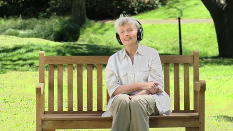 Elderly-woman-listening-to-musicon-a-bench