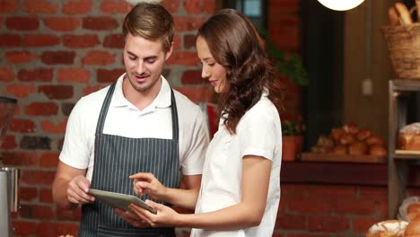 Smiling-waiter-using-tablet-with-a-customer