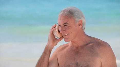 Elderly-man-listening-to-a-seashell