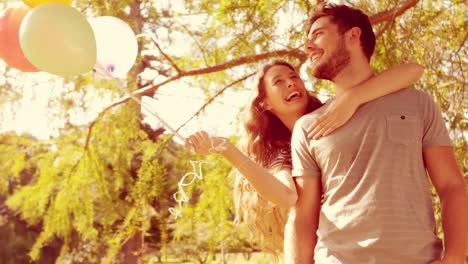 Happy-couple-hugging-in-park-and-holding-balloon-