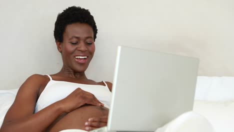 Pregnant-woman-using-video-chat-on-bed