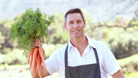 Smiling-farmer-handing-a-bunch-of-carrots