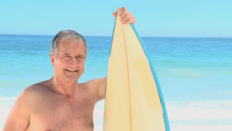 Elderly-man-posing-with-a-surfboard
