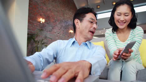 Asian-couple-using-media-devices