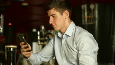 Man-using-phone-at-the-bar