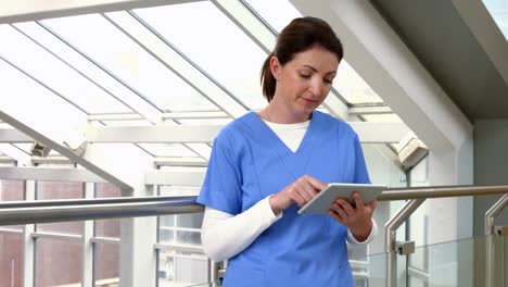 Nurse-using-tablet-pc-in-hallway