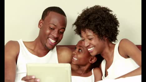 Cute-family-using-tablet-in-bed
