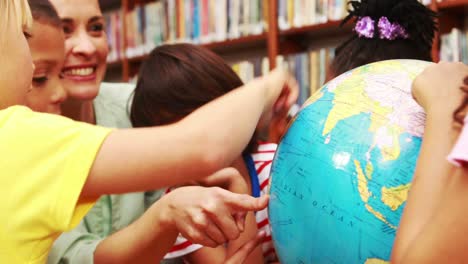 Pupils-and-teacher-looking-at-globe-in-library