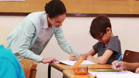 Teacher-helping-pupil-in-classroom