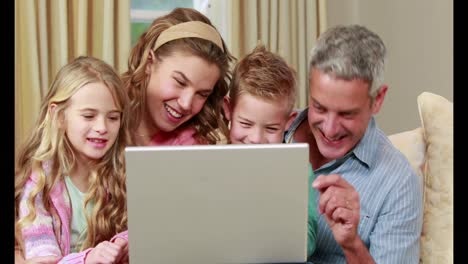 Familia-Feliz-Usando-Una-Computadora-Portátil-En-El-Sofá