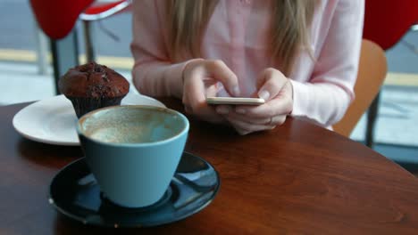 Pretty-blonde-having-a-coffee-texting-on-phone