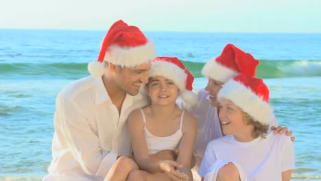 Süße-Familie-Mit-Weihnachtsmützen-Am-Strand
