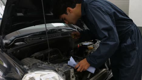 Handsome-mechanic-checking-oil-in-a-car-engine