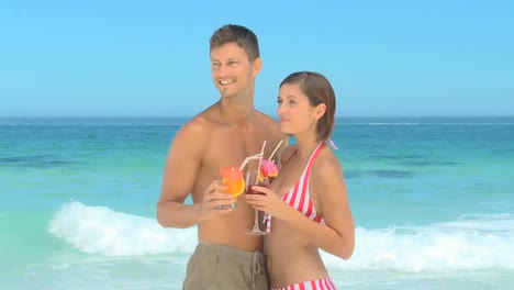 Sweet-couple-sharing-cocktails-on-a-beach