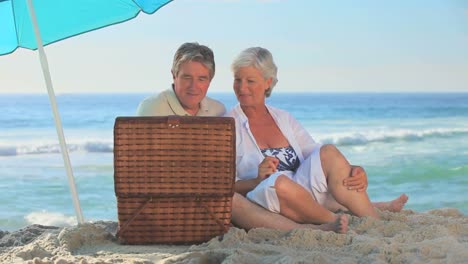 Mature-couple-picnicking-on-a-beach