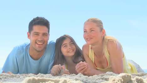 Glückliche-Eltern-Und-Tochter-Liegen-Am-Strand