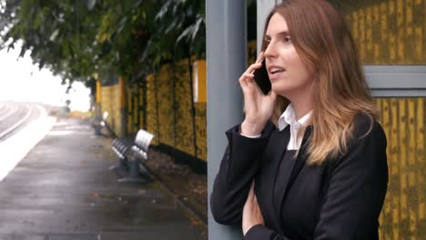 Businesswoman-waiting-for-a-train-on-the-phone