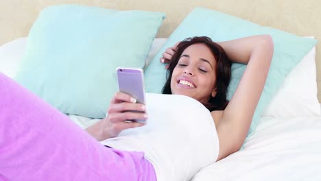 Smiling-woman-texting-on-bed-